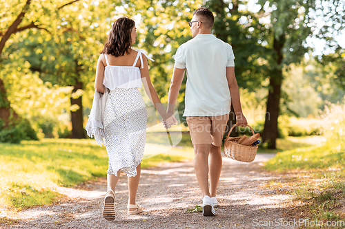 Image of happy couple with picnic basket at summer park