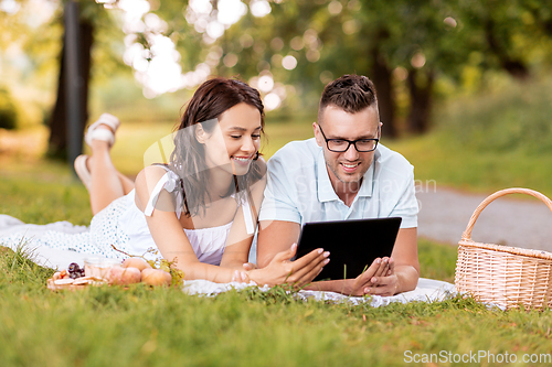 Image of happy couple with tablet pc at picnic in park