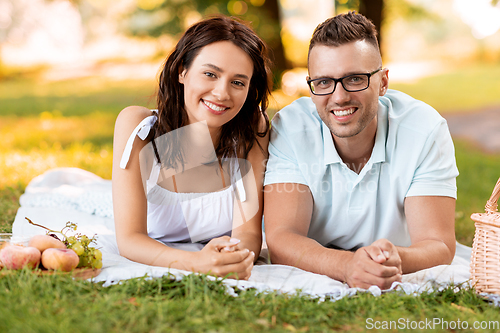 Image of happy couple on picnic blanket at summer park