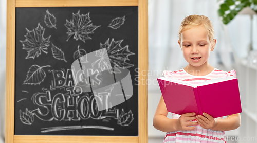 Image of smiling little student girl reading book