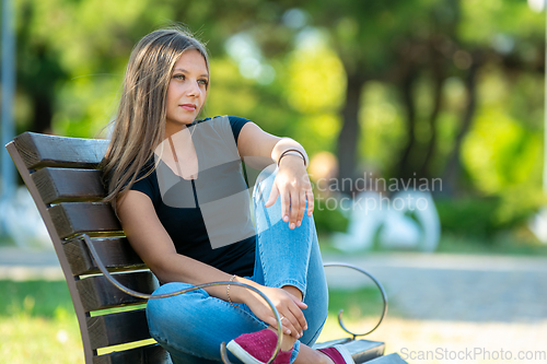 Image of Girl sitting on a bench in the park, close-up