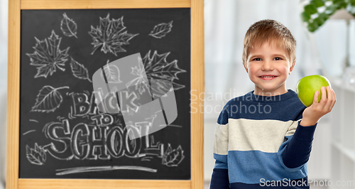 Image of little student boy with apple at school blackboard