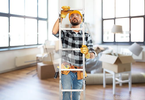 Image of male builder in helmet climbing up ladder at home