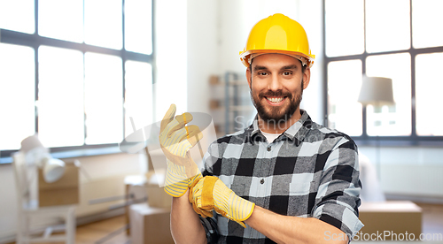 Image of happy male builder in helmet and gloves at home