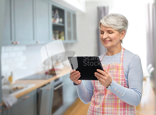 Image of smiling senior woman in apron with tablet computer