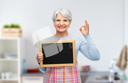 Image of senior woman in apron with chalkboard showing ok