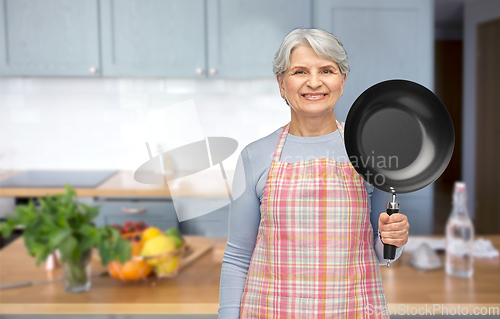 Image of smiling senior woman in apron with frying pan