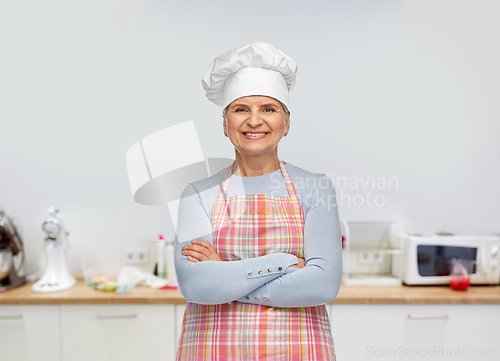 Image of smiling senior woman or chef in toque in apron