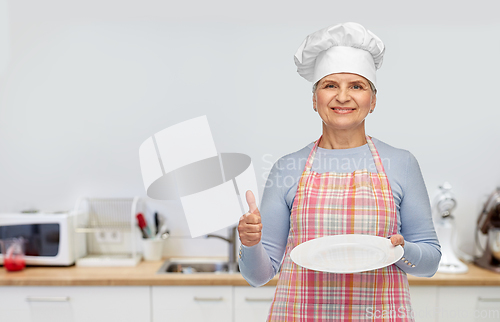 Image of smiling senior woman or chef holding empty plate