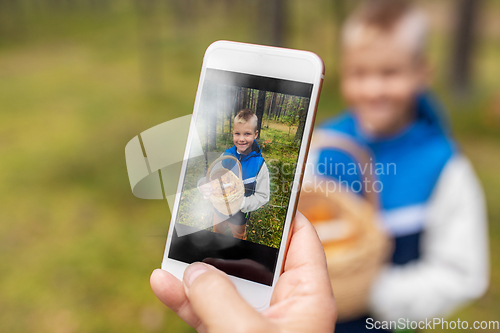 Image of parent photographing grandson with mushrooms