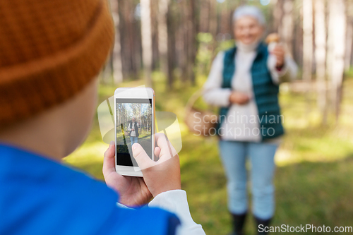 Image of grandson photographing grandmother with mushroom