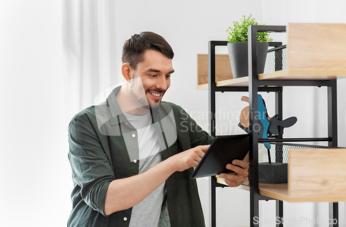 Image of happy smiling man with tablet pc at shelf at home