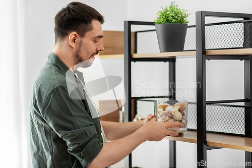 Image of man decorating home with seashells in vase