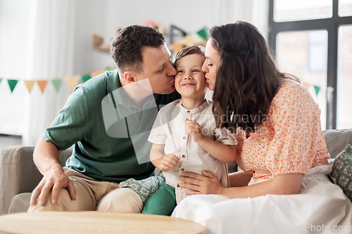 Image of happy parents kissing little son at birthday party