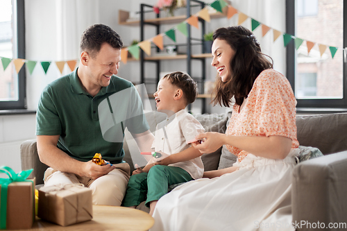 Image of happy family with gifts and party blowers at home