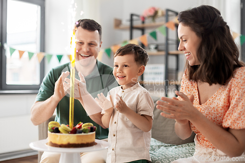 Image of happy family with birthday cake at home