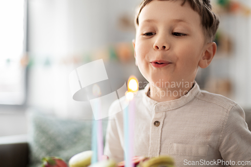 Image of happy little boy blowing candles on birthday cake