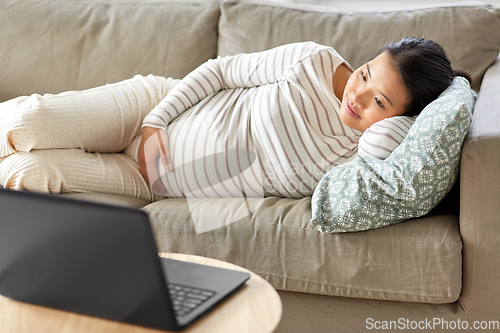 Image of happy pregnant asian woman with laptop at home