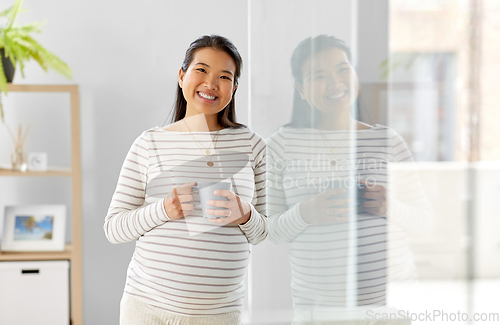 Image of happy pregnant woman drinking tea at home