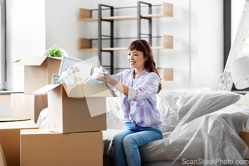 Image of happy woman unpacking boxes and moving to new home