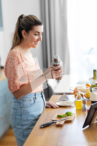 Image of woman with tablet pc making cocktails at kitchen