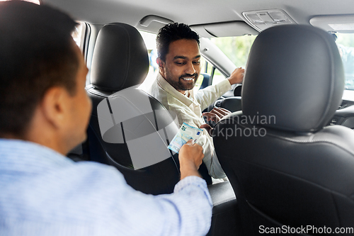 Image of passenger giving money to smiling taxi car driver