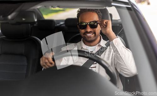 Image of smiling indian man in sunglasses driving car