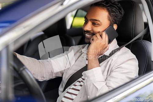 Image of indian man driving car and calling on smartphone