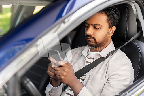 Image of indian man in car using smartphone