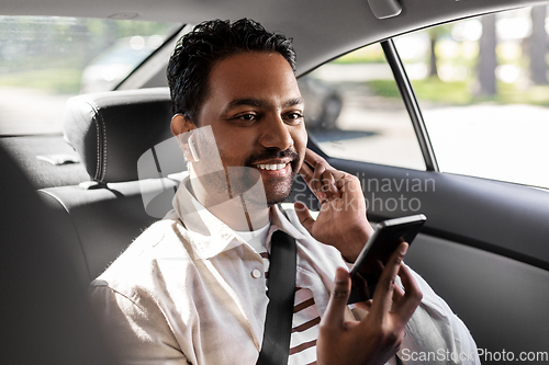 Image of passenger with earphones and cellphone in taxi car