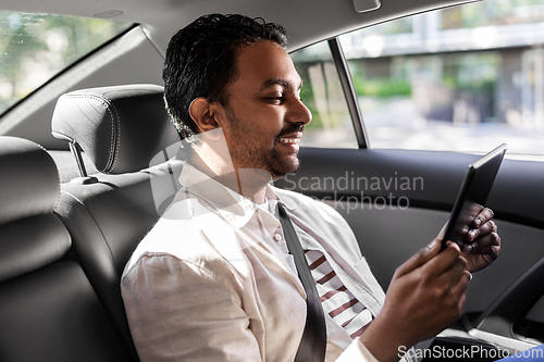 Image of indian male passenger with tablet pc in taxi car