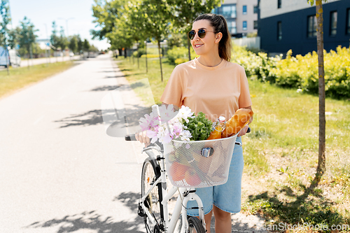 Image of woman with food and flowers in bicycle basket