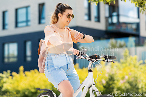 Image of woman with smart watch riding bicycle in city