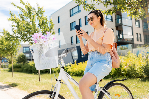 Image of woman with smartphone on bicycle in city