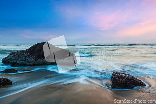 Image of waves and rocks on beach of sunset