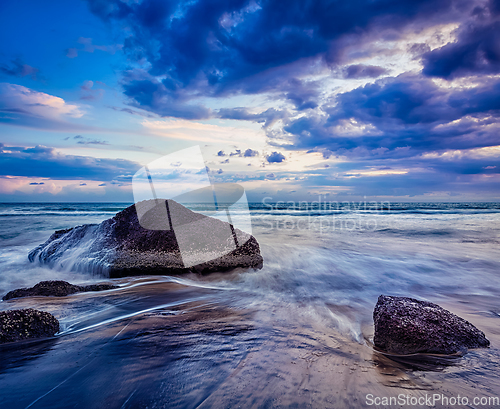 Image of waves and rocks on beach of sunset