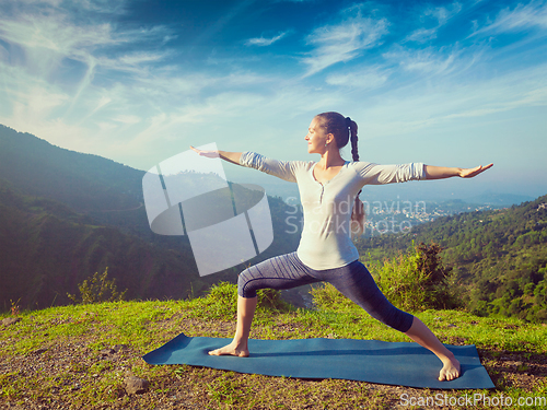 Image of Woman doing yoga asana Virabhadrasana 2 - Warrior pose outdoors