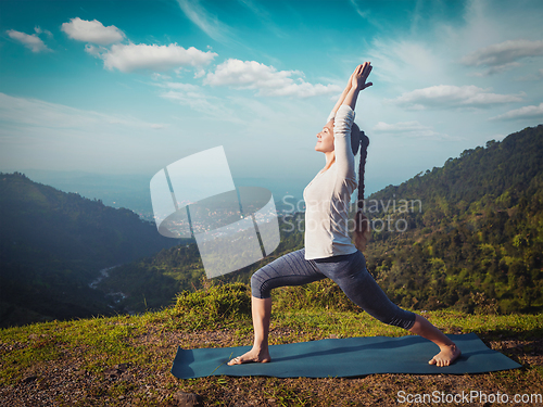 Image of Woman doing yoga asana Virabhadrasana 1 - Warrior pose outdoors