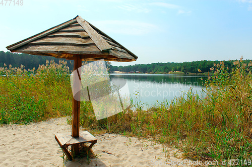 Image of wooden umbrella on the sand near lake in the forest