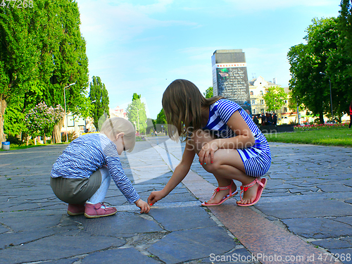 Image of little sisters write on the road in the park