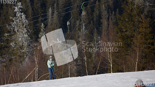 Image of Happy young woman on button ski lift going uphill