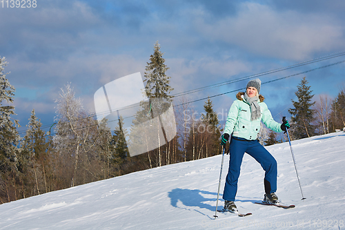 Image of young beautiful skier rides a ski resort on a background of blue sky