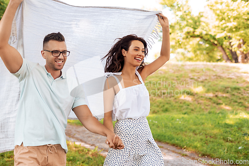 Image of happy couple with picnic blanket at summer park