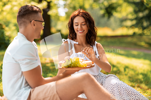 Image of happy couple having picnic at summer park