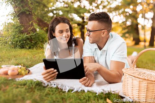 Image of happy couple with tablet pc at picnic in park