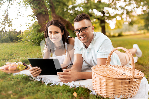 Image of happy couple with tablet pc at picnic in park