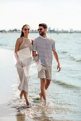 Image of happy couple walking along summer beach