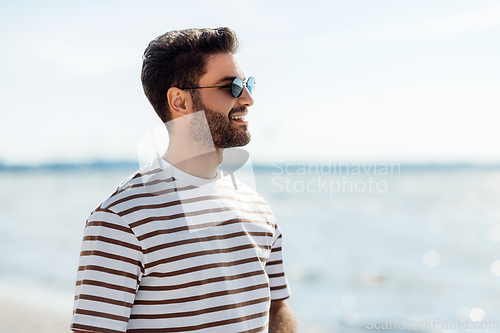 Image of smiling young man in sunglasses on summer beach