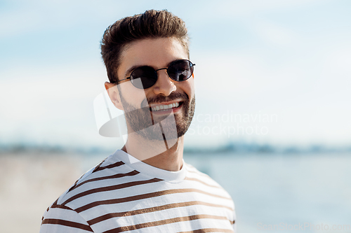 Image of smiling young man in sunglasses on summer beach