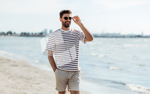 Image of smiling young man in sunglasses on summer beach